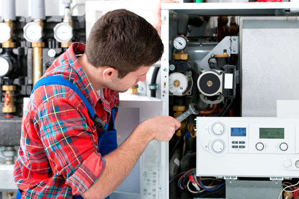 HVAC technician inspecting and repairing boiler controls in West Valley City
