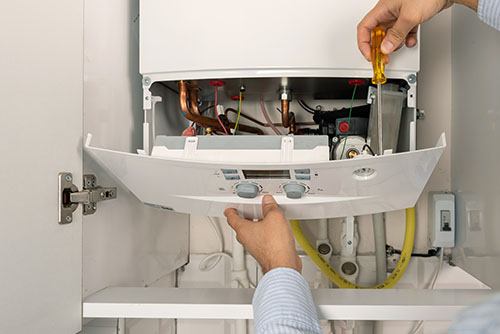 HVAC technician repairing an indoor boiler in West Valley City