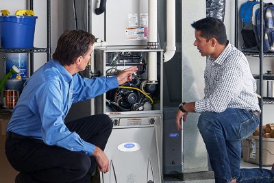 65df8c11f3e4c468cbd351a5_furnace repair vs replacement – Copy HVAC technician explaining furnace repair and maintenance to a homeowner in West Valley City, UT