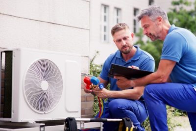 ac-installation-in-claremont-ca HVAC technicians reviewing an outdoor air conditioning unit in West Valley City, UT